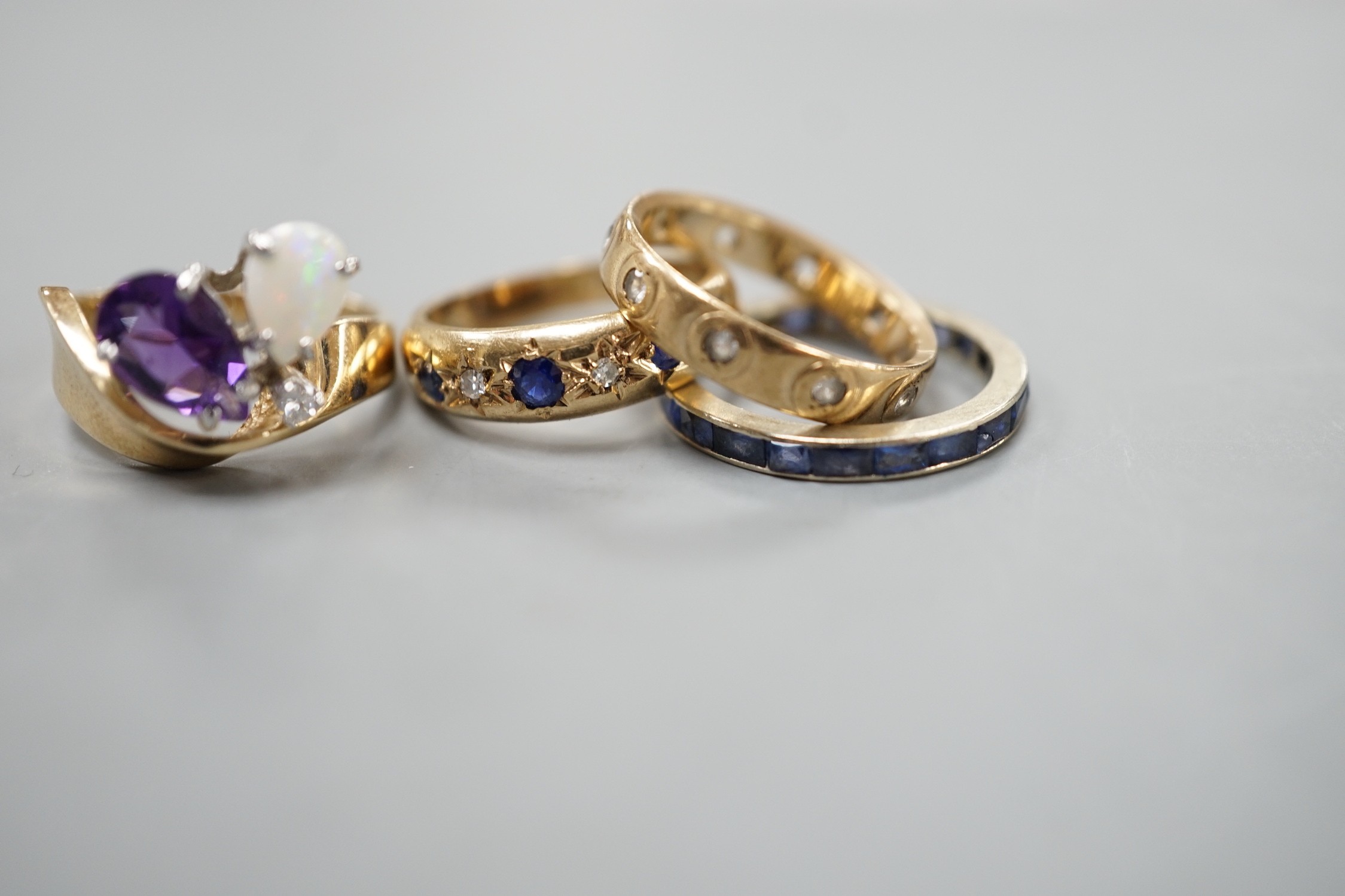 A 10k yellow metal, amethyst, white opal and diamond set dress ring, size N, gross weight 4.6 grams, two 9ct and gem set rings and a white metal and sapphire? set full eternity ring, gross weight 8.2 grams.